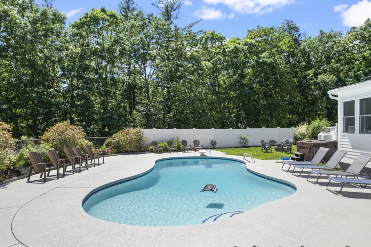 Une piscine avec des chaises longues, un jacuzzi et un bâtiment blanc en arrière-plan.