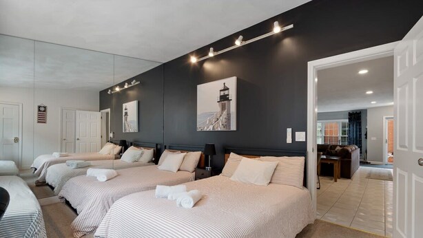 A hotel room with three beds, a dark accent wall, and a view of the living area. - Heart of Southie - Hot Tub + Walk to Top Bars (Boston)