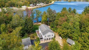 A lakeside property with a large house, a dock, and a forested area.