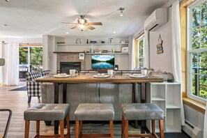 Una cocina moderna con una isla grande, taburetes de bar y un televisor.