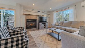 A living room with a fireplace, a sofa, a coffee table, and checkered chairs.