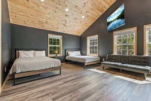 Un dormitorio con dos camas, un sofá y una televisión en la pared.