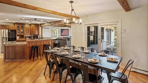 A spacious kitchen with wooden cabinets, a central island, and a dining area with a long table and chairs.