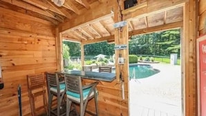 A wooden cabin with a dining area and a view of a swimming pool.
