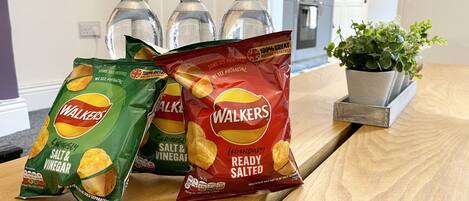 Drie zakken Walkers chips op een houten tafel, met een potplant ernaast.