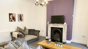 Una sala de estar con un sofá, una mesa de centro, una chimenea y un televisor montado encima.