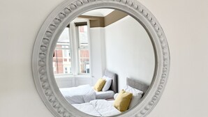 Un espejo redondo con un marco decorativo en la pared.