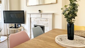 Een woonkamer met een televisie, open haard en een plant.