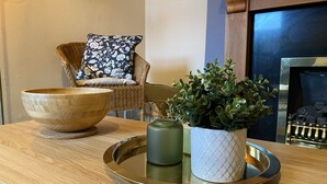 Una mesa de madera con una bandeja que sostiene un cuenco, una planta en maceta y una vela.
