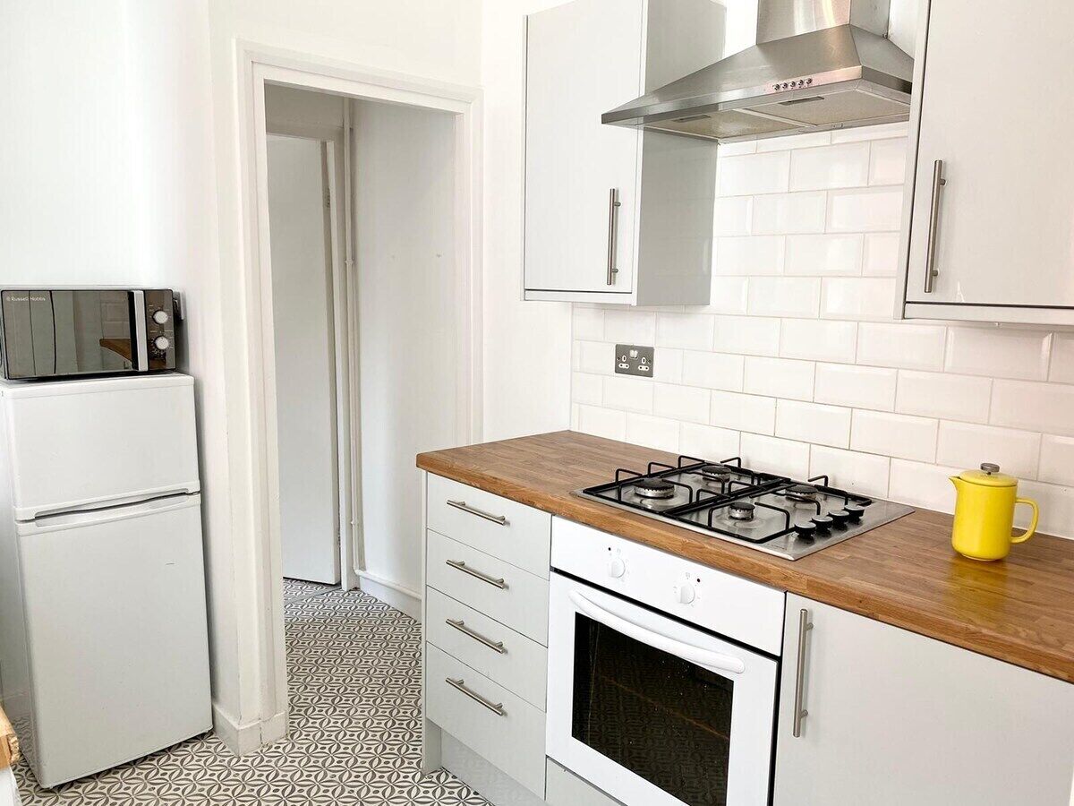A compact kitchen with a gas stove, white cabinets, a microwave, and a patterned floor.