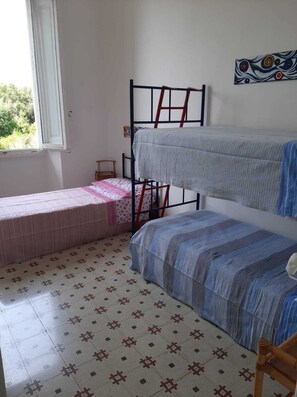 A dormitory room with bunk beds, a window, and patterned floor tiles. - The White House on the sea (Rosignano Marittimo)