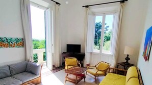 A living room with a sofa, chairs, a table, a TV, and a balcony. - The White House on the sea (Rosignano Marittimo)