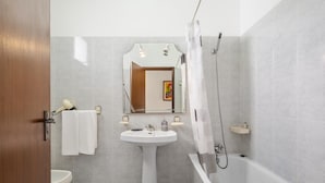 A bathroom with a pedestal sink, a mirror, a shower, and a toilet. - Escapadinha do Sol by Homie (Porto Santo)