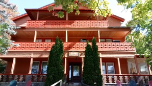 Un immeuble à plusieurs étages, doté d’une façade rouge, d’une enseigne indiquant « Appartements Tiroil » et d’une entrée principale avec une porte en verre.