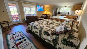 Une chambre confortable avec un grand lit, un petit bureau et une télévision. Une porte-fenêtre coulissante donne accès à un balcon.