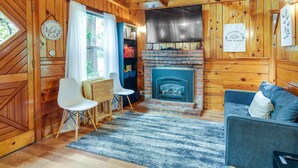 Un intérieur de chalet chaleureux avec une cheminée, des murs en bois, un canapé et un coin repas.