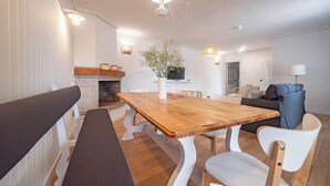 Et moderne spiseområde med et træbord, hvide stole og en pejs.