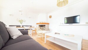 En moderne stue med sofa, hvidt sofabord, pejs og fjernsyn monteret på væggen.