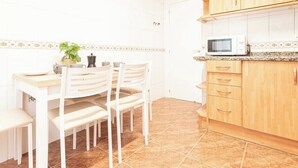 A kitchen with white cabinets, a microwave, a coffee maker, and a clock on the wall.