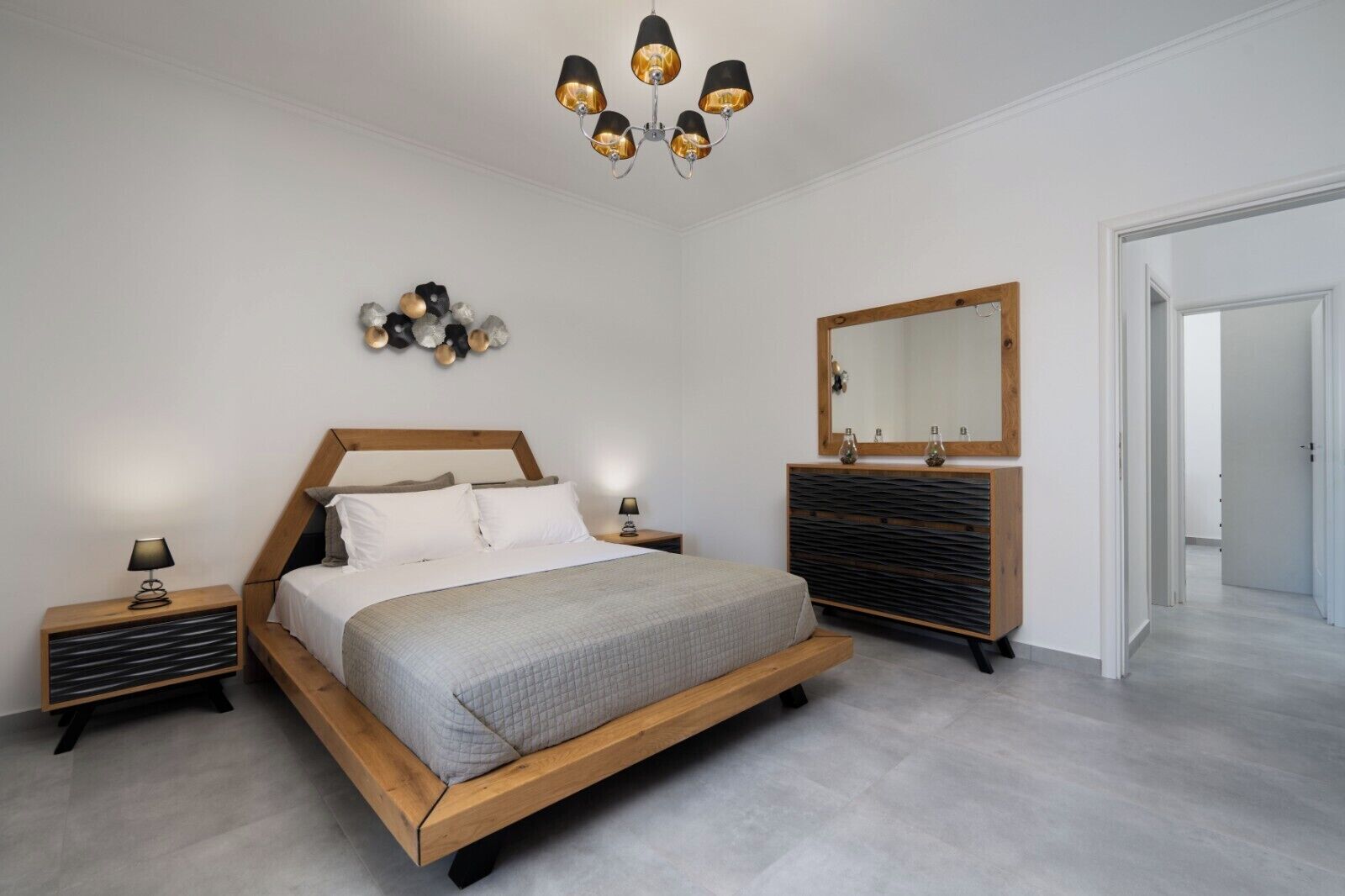 Une chambre à coucher moderne avec un lit en bois, des tables de chevet, une commode, un miroir et un lustre.
