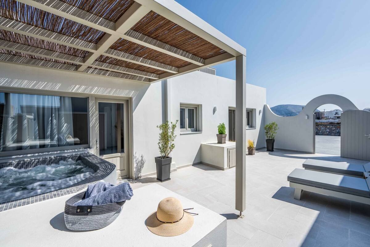 Un espacio exterior moderno con un jacuzzi, sillas de descanso y plantas en macetas.