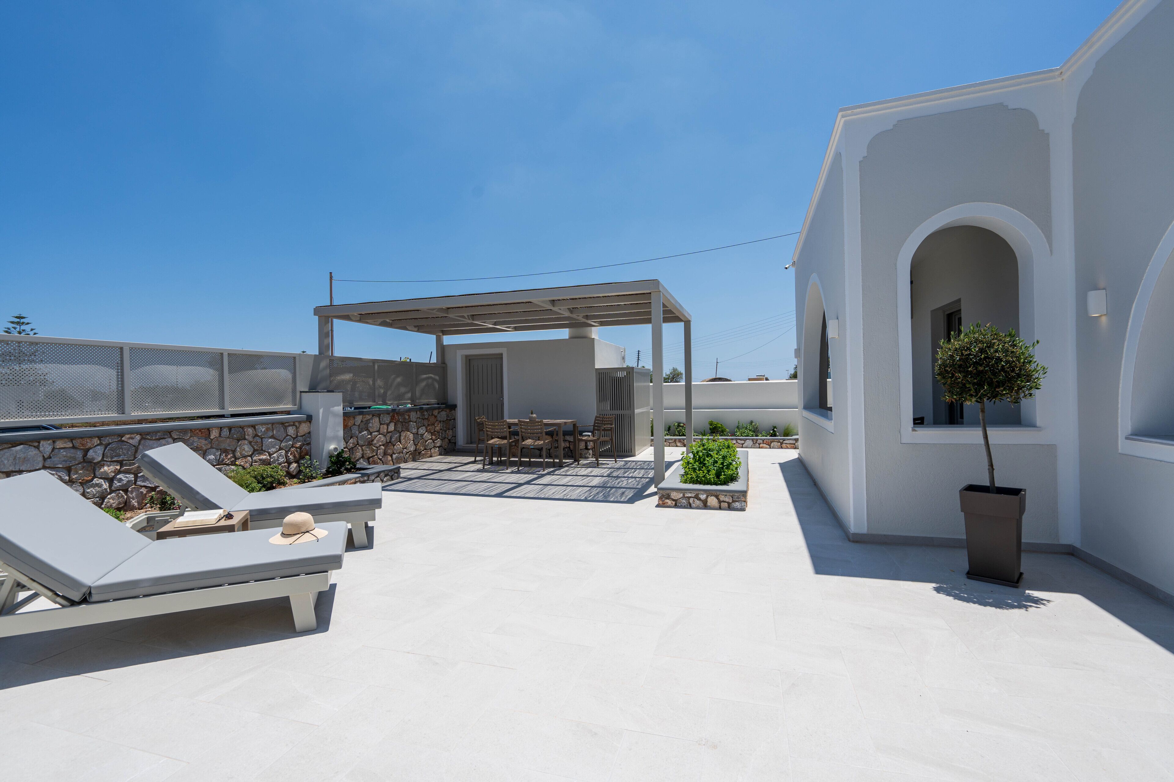 Een terras op het dak met loungezetels, een tafel en een pergola.