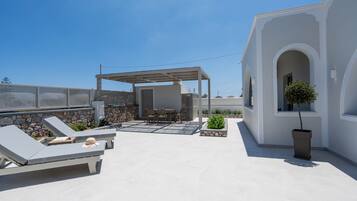 Een terras op het dak met loungezetels, een tafel en een pergola.