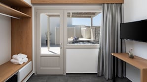 Een hotelkamer met een schuifdeur naar een balkon, een televisie aan de muur en een kleine tafel met een vaas.