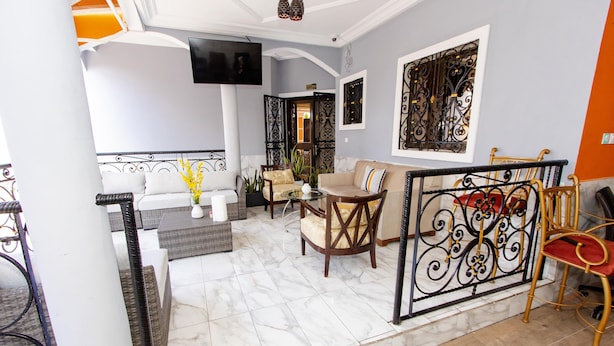 A modern living room with a sofa, armchairs, a coffee table, and a TV mounted on the wall.