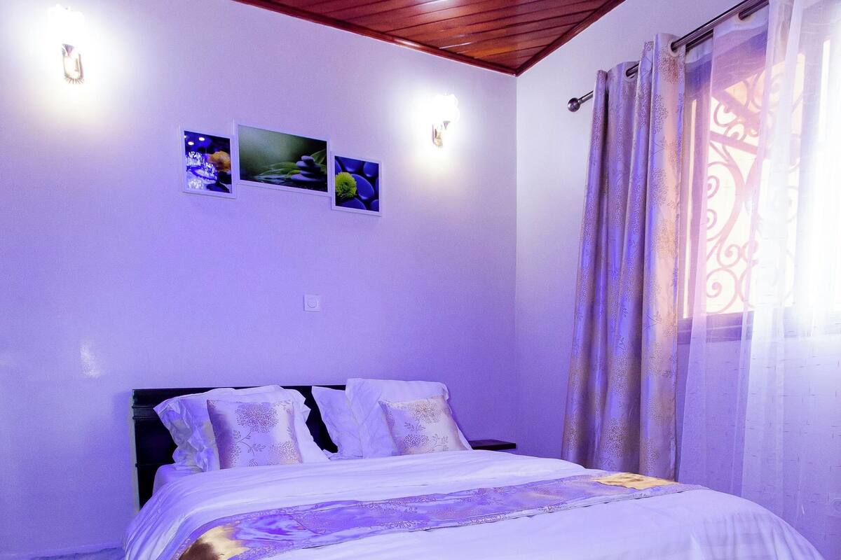 Un dormitorio con techo de madera, una cama con ropa blanca, una alfombra mullida y un aire acondicionado instalado en la pared.