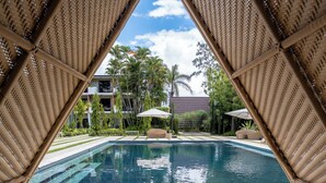 A pool area with a clear view of the pool, lounge chairs, and a building in the background. - Hotel Pinar Dorado by Gran Jimenoa (Jarabacoa)