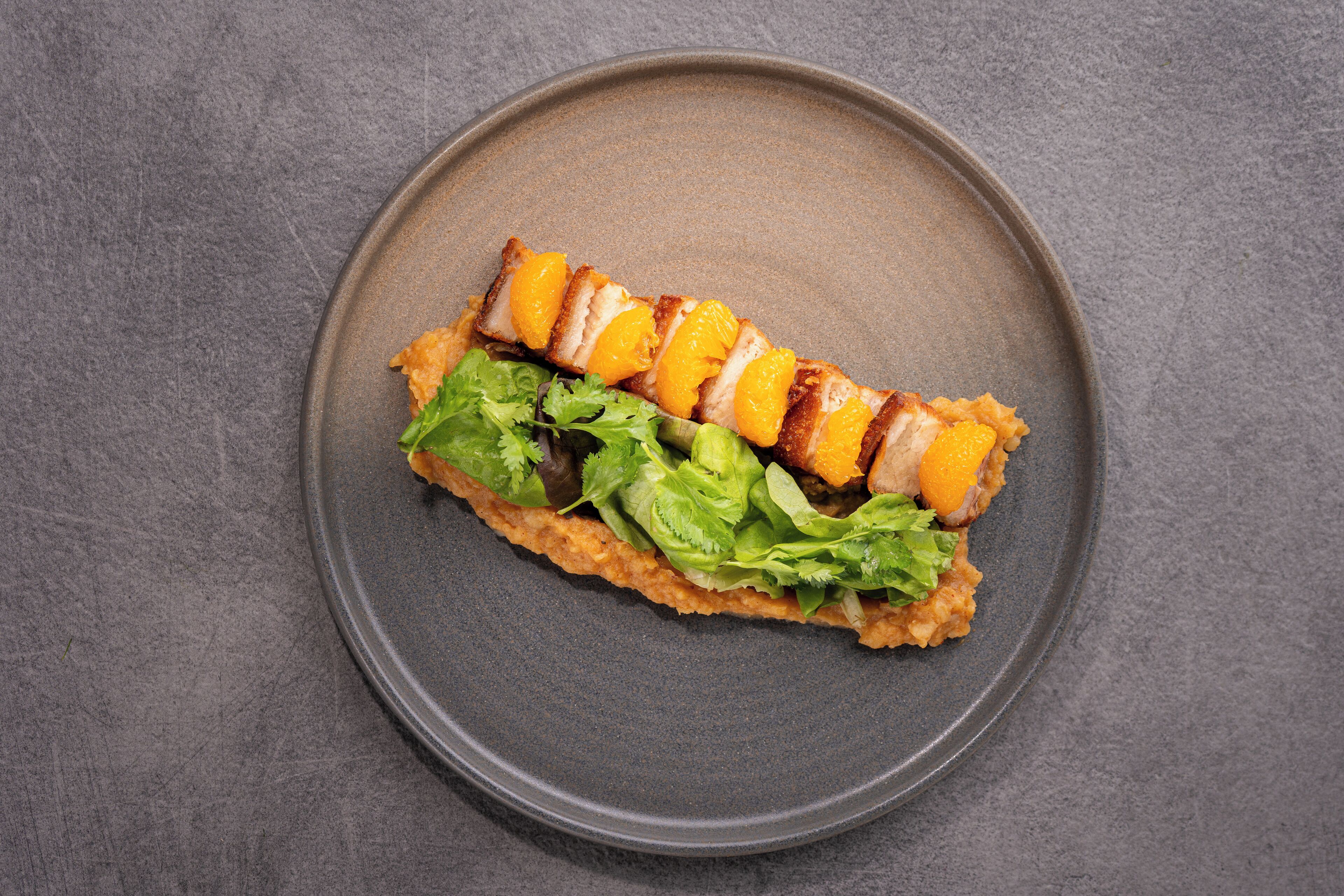 A plate with a sandwich-like food item, possibly a wrap, on a dark plate.