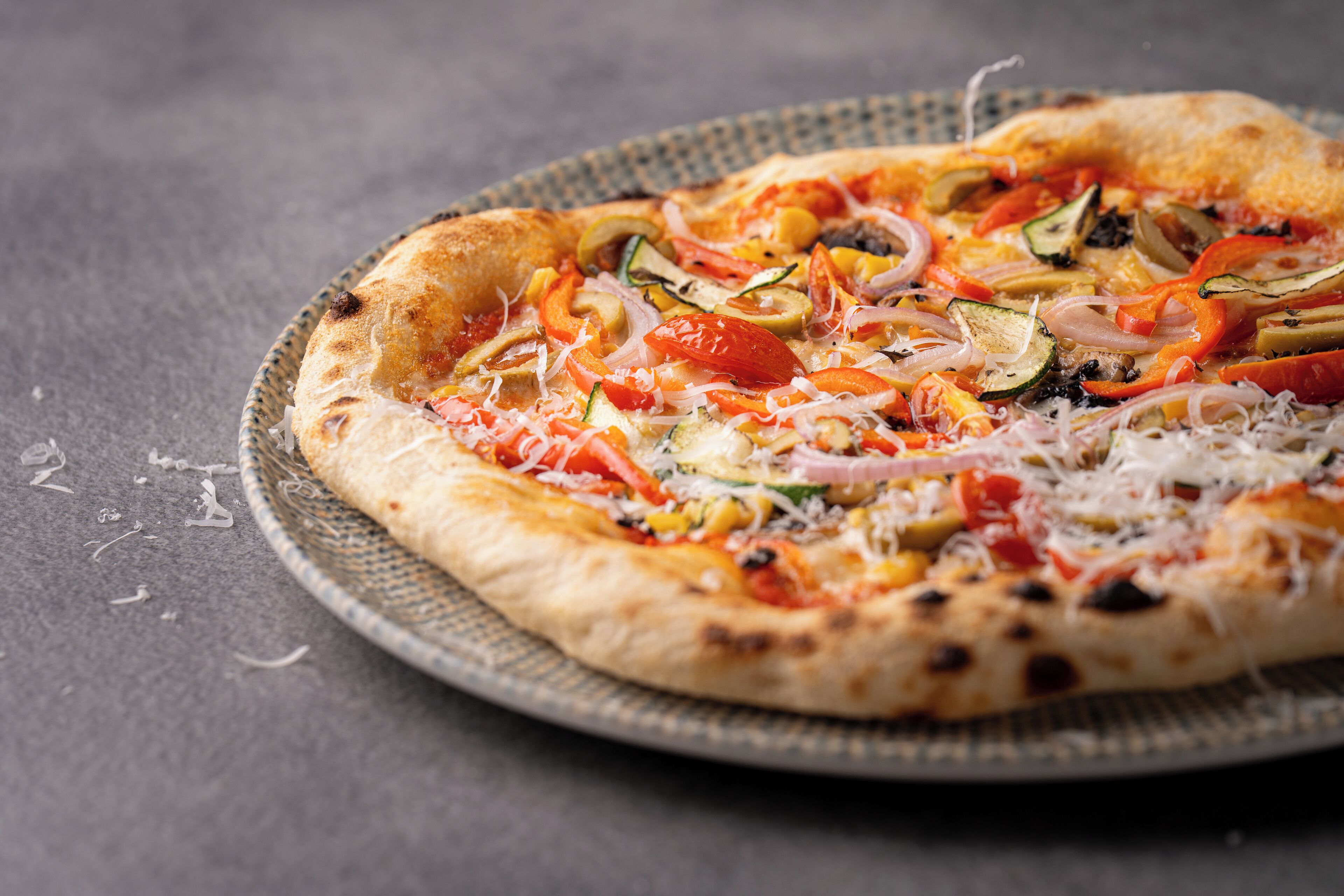 A pizza with various vegetables and cheese on a round plate.