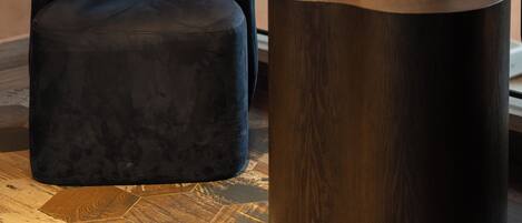 A dark blue chair and a round wooden side table with a textured white pot containing a plant.