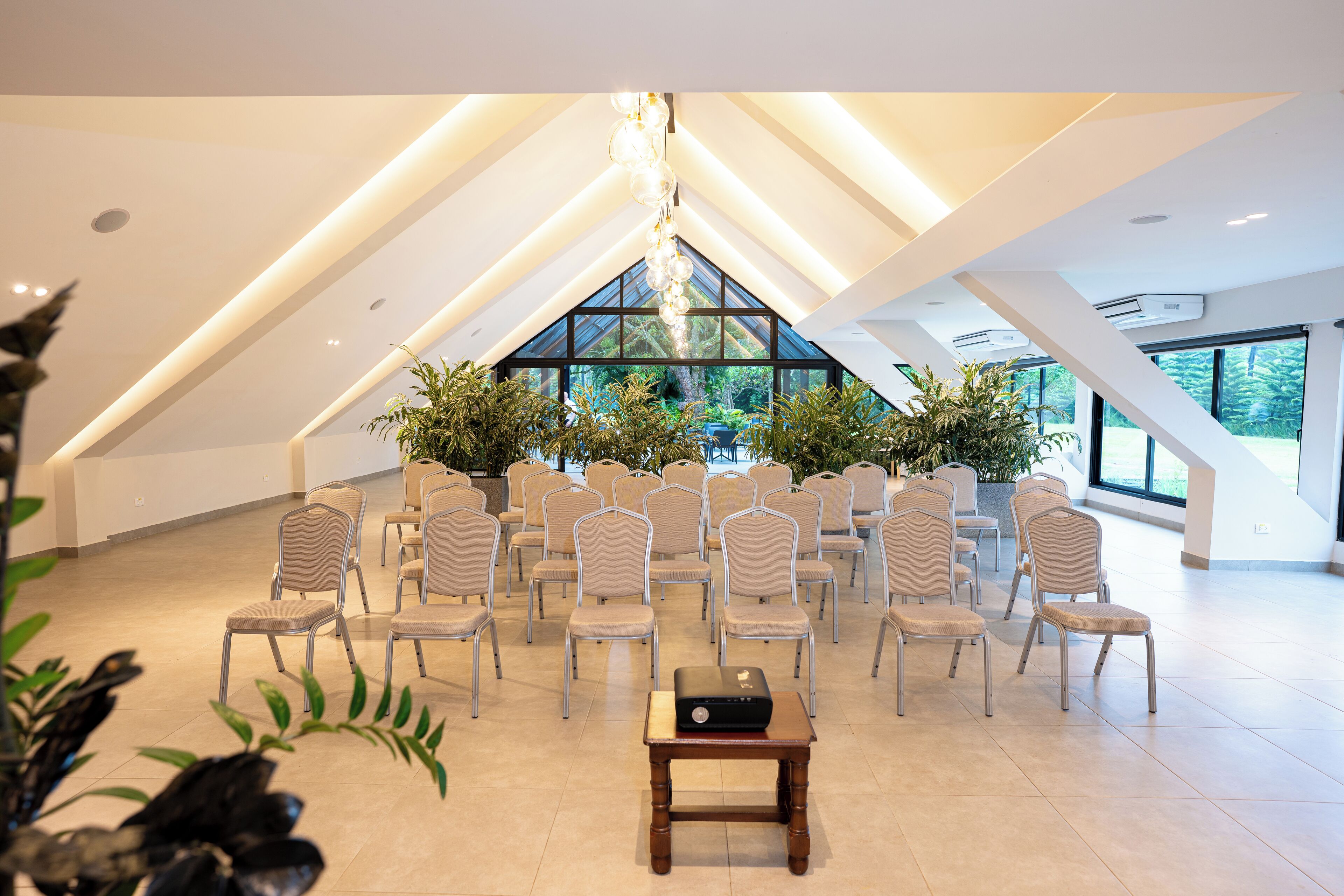 A conference room with a high ceiling, arranged chairs, and a laptop on a table.