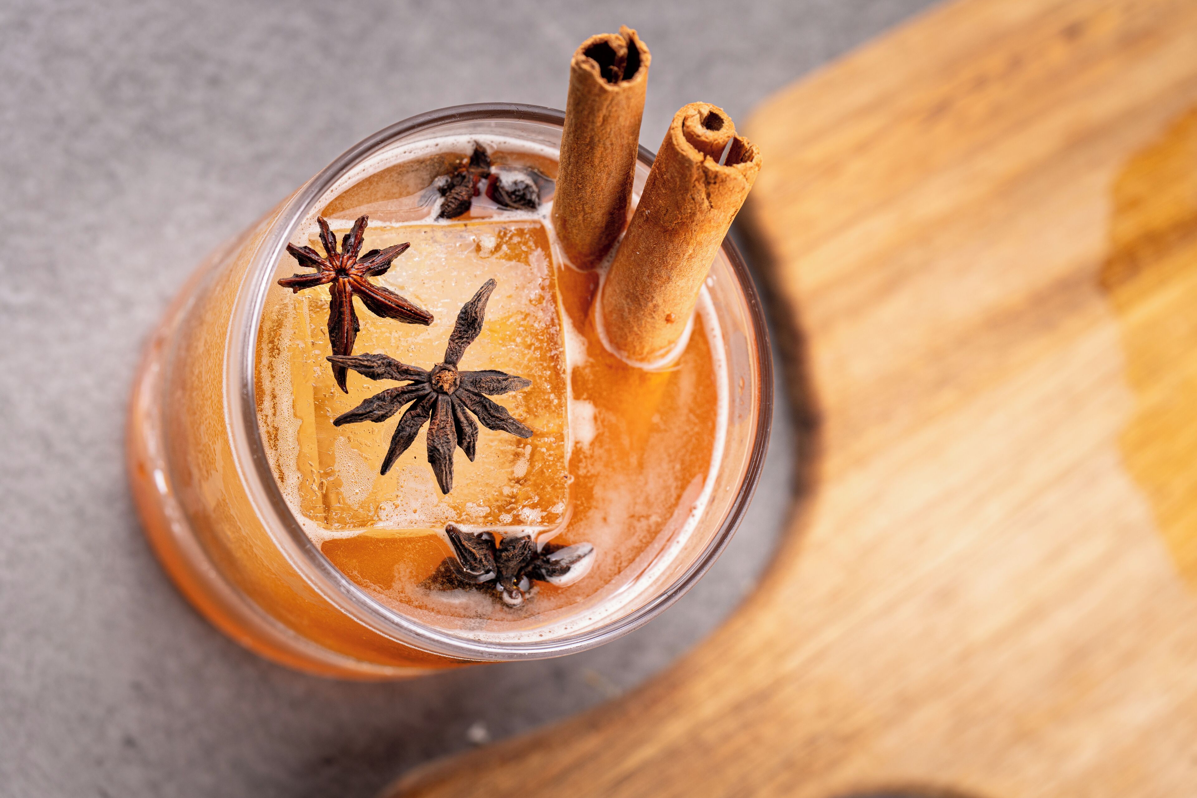 A glass with a beverage garnished with star anise and cinnamon sticks.