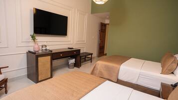 Habitación de hotel con dos camas, televisor, escritorio y cubo de basura.
