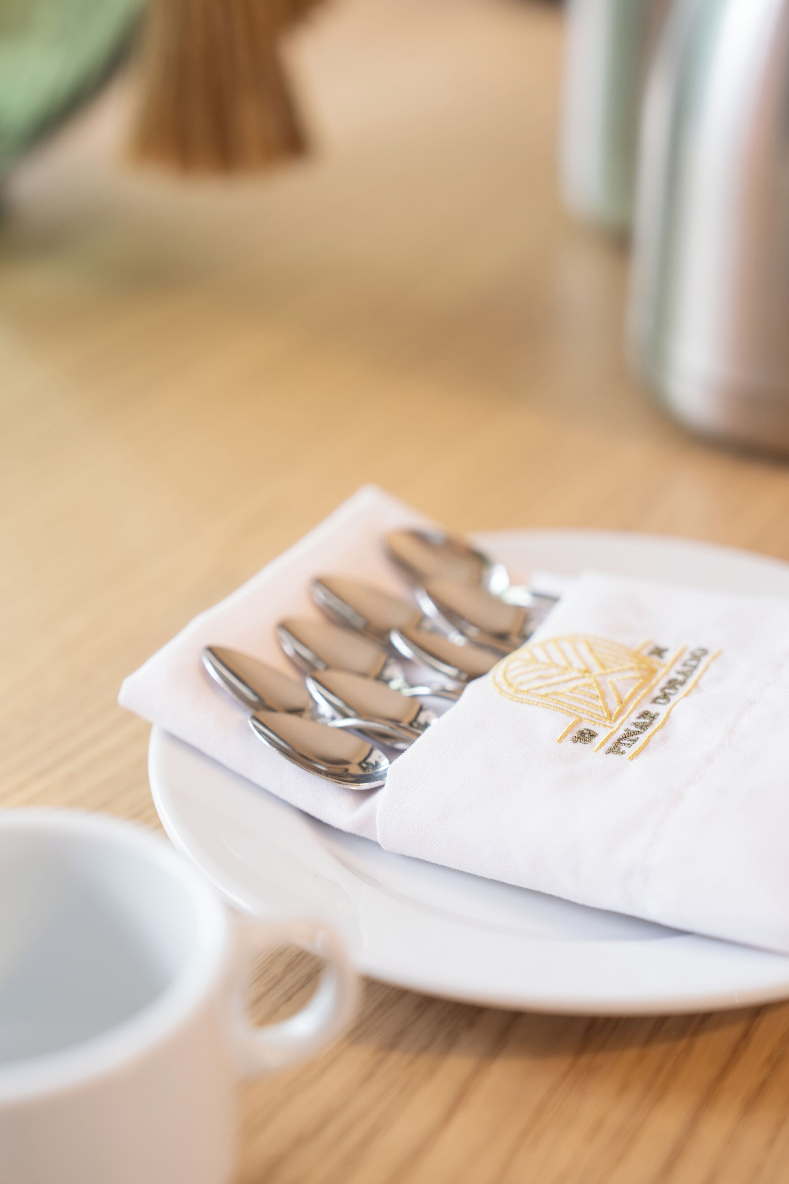 A white plate with a napkin and four silver spoons on it.