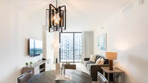A modern living room with a round dining table, a sofa, a TV mounted on the wall, and a large window with a city view. - Location, location, location. Best area of Doral (Doral)