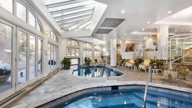 An indoor swimming pool with a stone floor, surrounded by lounge chairs and a glass ceiling. - Vail Sonnenalp King Hotel Room (Vail)
