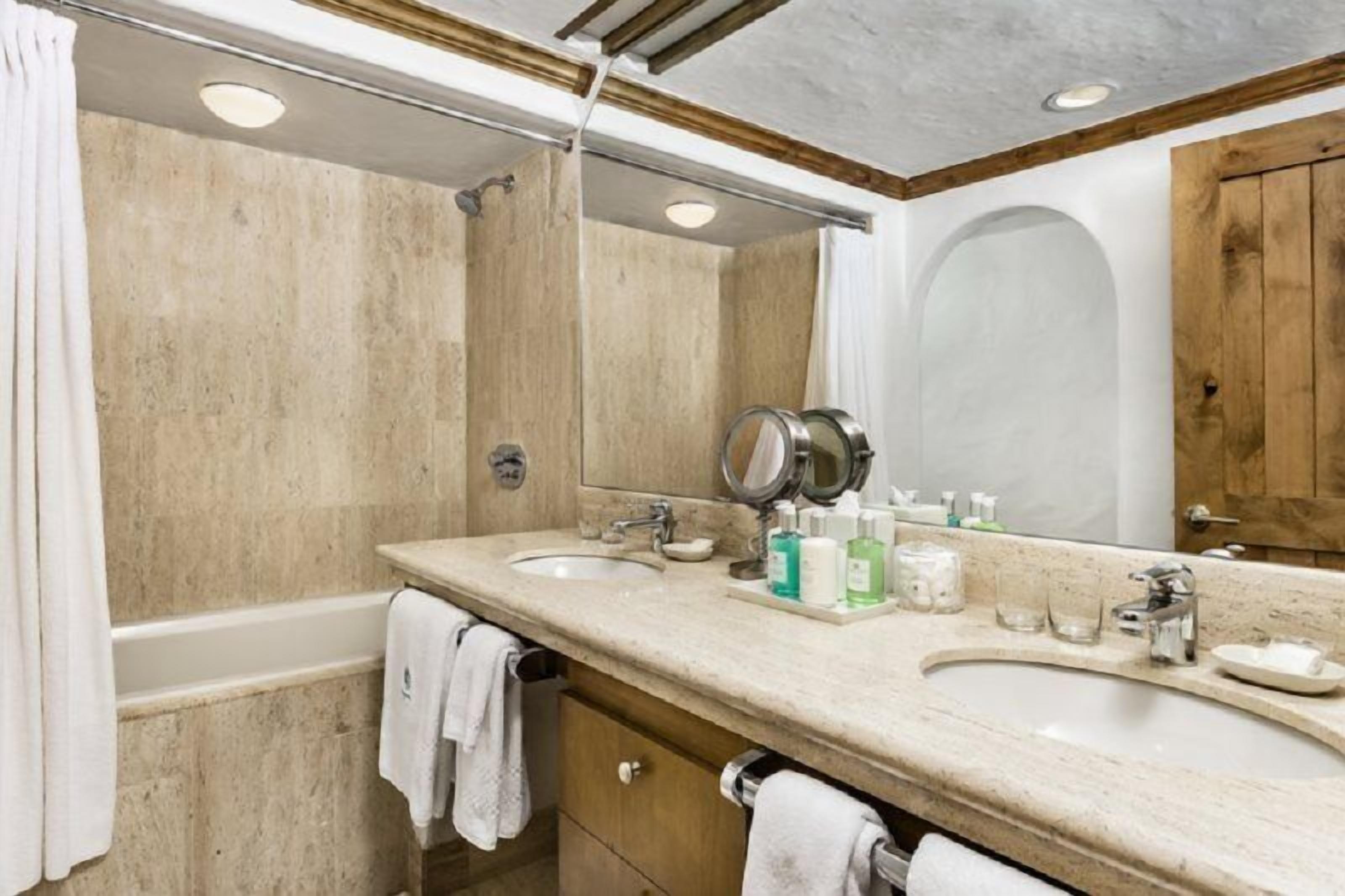 A bathroom with two sinks, a large mirror, and a shower.