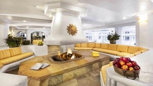 A modern lounge area with a stone fire pit, yellow-striped sofas, and a fruit bowl. - Vail Sonnenalp King Hotel Room (Vail)