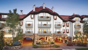 A large, multi-story hotel with a central courtyard, multiple balconies, and a stone archway. - Vail Sonnenalp King Hotel Room (Vail)