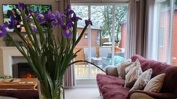A living room with a sofa, a table with a vase of flowers, a TV, and a fireplace.