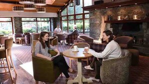 A cozy indoor seating area with wooden furniture and large windows.