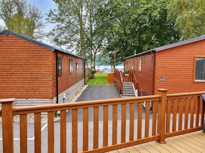 A wooden deck leading to a row of cabins with a view of a lake.