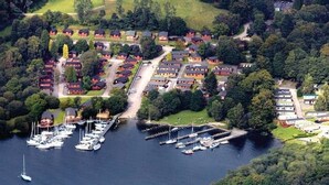 An aerial view of a marina with multiple boats docked, surrounded by residential buildings and greenery.
