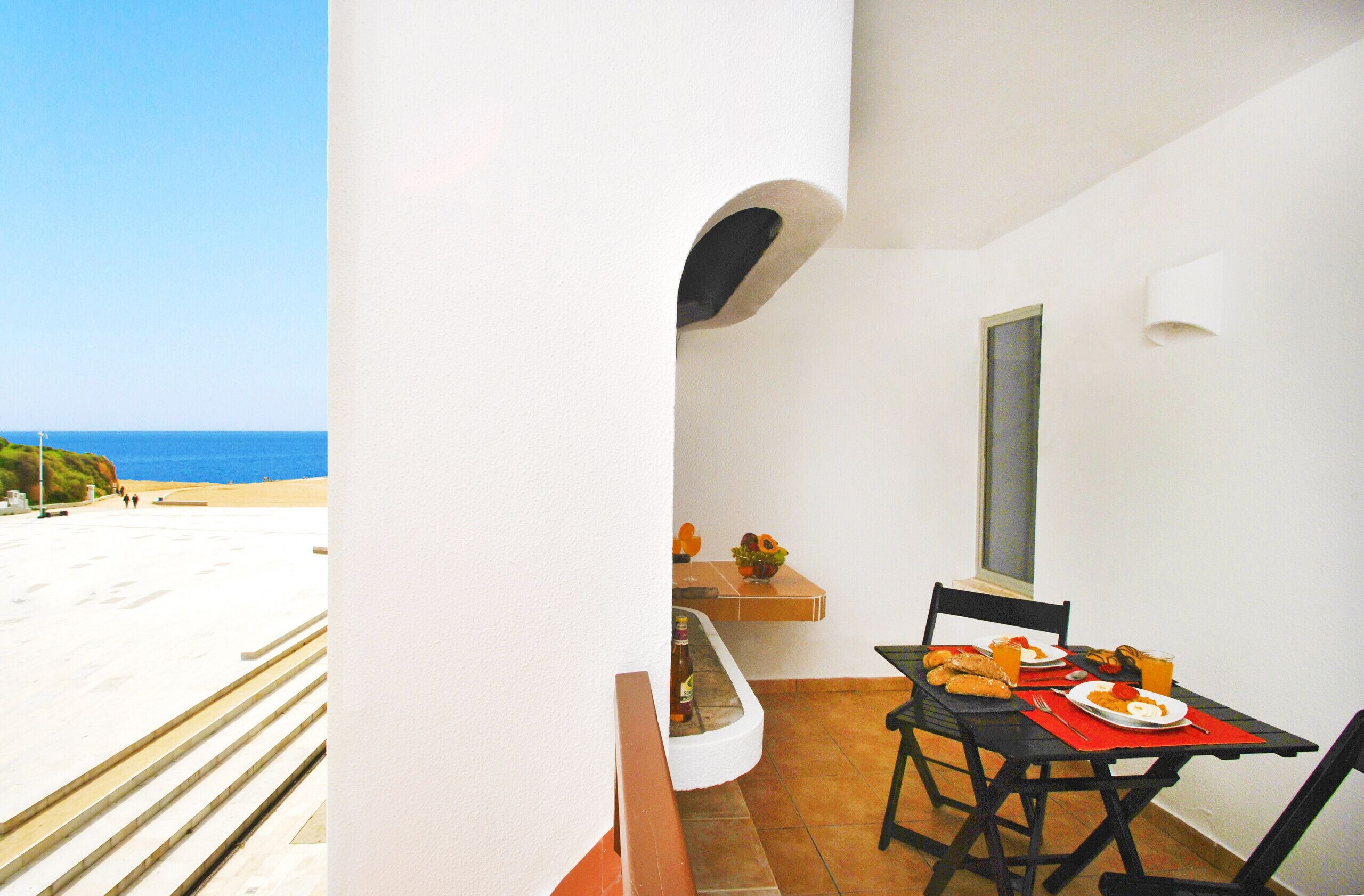 Een balkon met een ontbijttafel, met uitzicht op een strand.