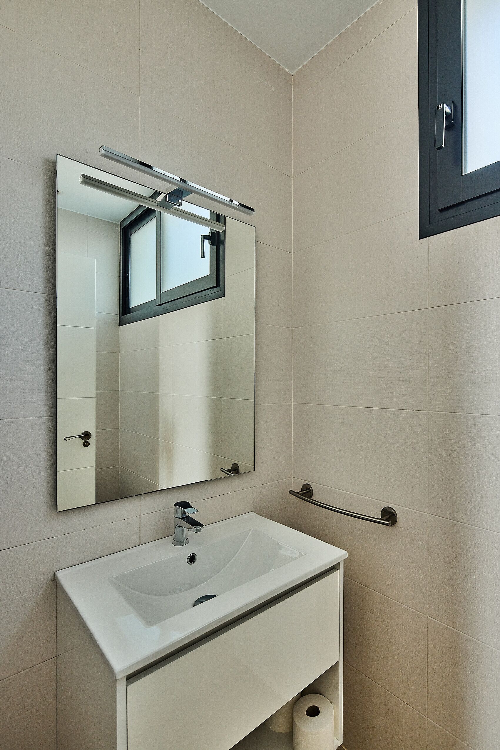Ein Badezimmer mit einem weißen Waschbecken, einem Spiegel und einer Toilette.