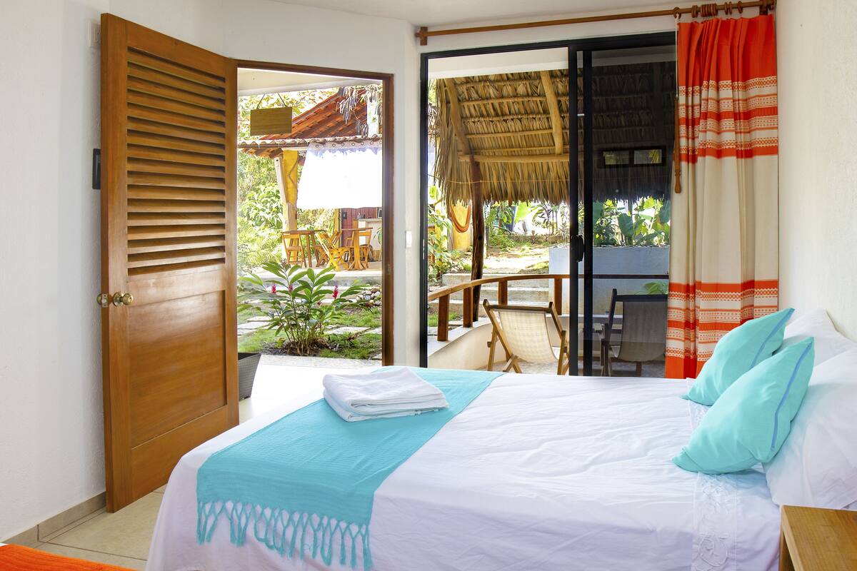 A bedroom with a bed, a window, and a view of the outside.